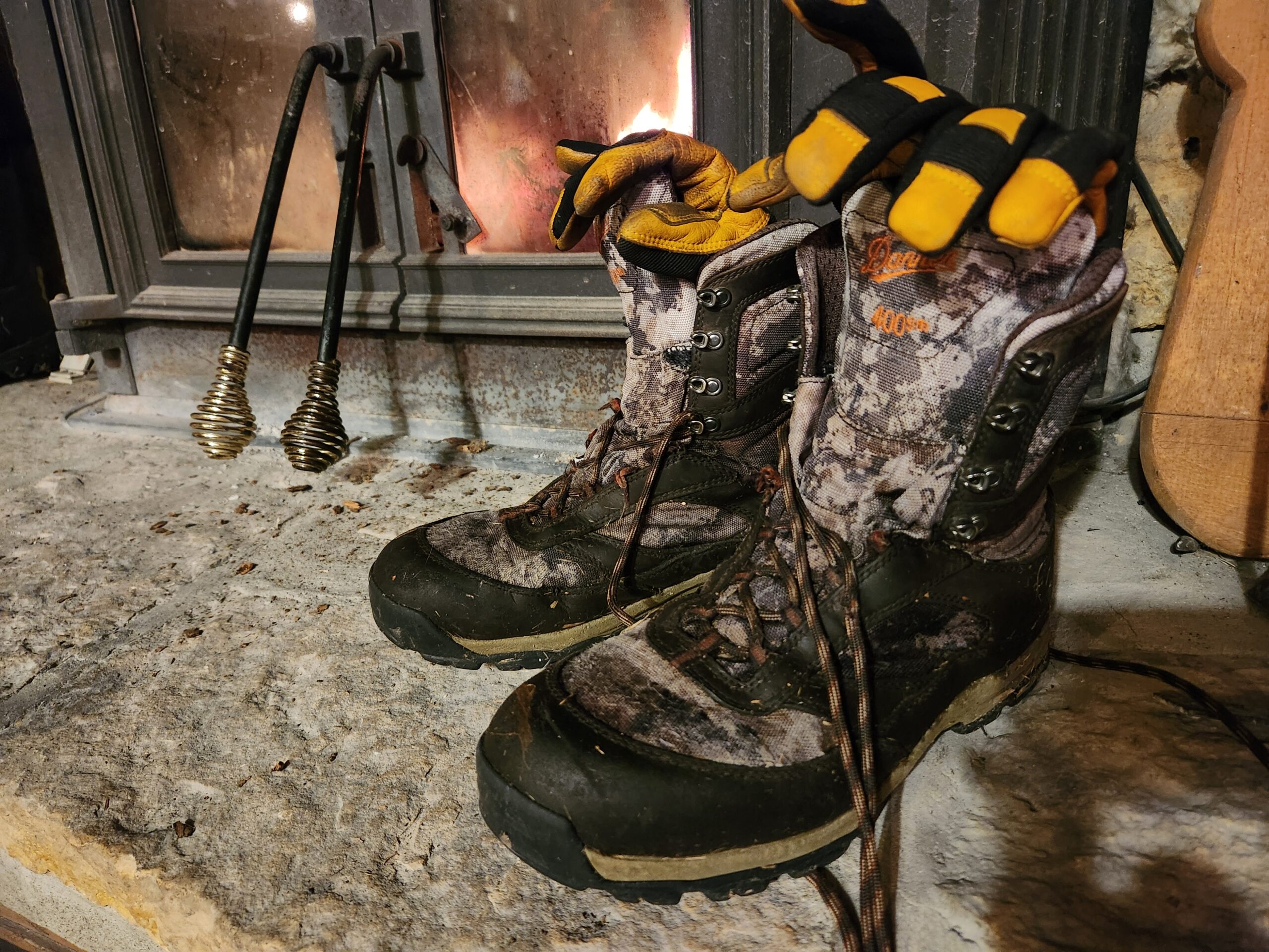 Danner boots drying by a fireplace